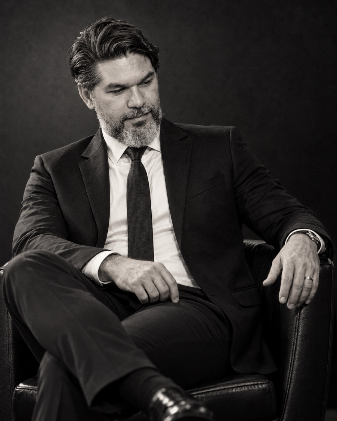 Retrato em preto e branco de Marcelo Grangeiro sentado numa poltrona